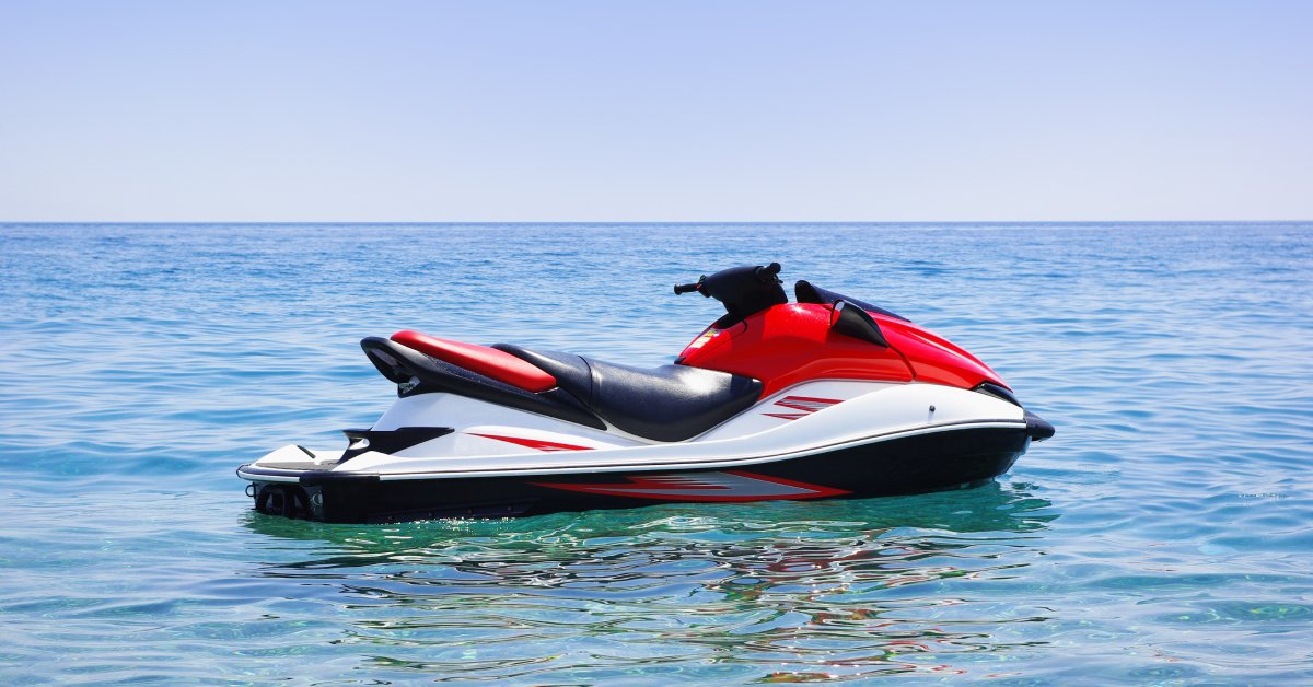 The Importance of Proper Jet Ski Battery Maintenance A red, black, and white jet ski sits alone on calm waters. It's a beautiful sunny day and there are no clouds.