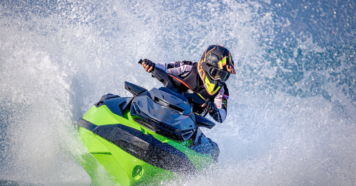 A close-up of a person riding their neon lime green jet ski, splashing in the water. They are also wearing a helmet.